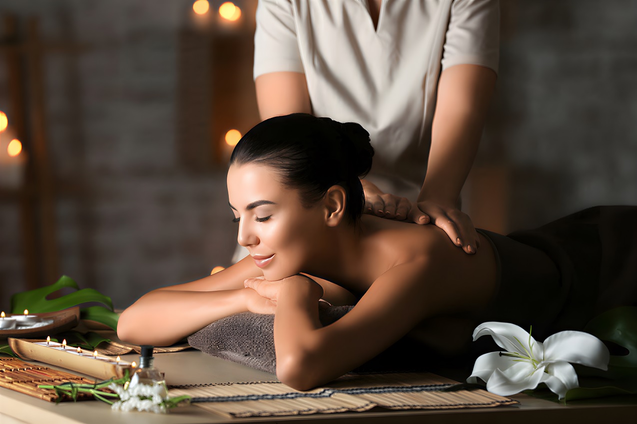 Professional massage therapist performing a relaxing body massage on a client lying face down with hands applying pressure to back muscles